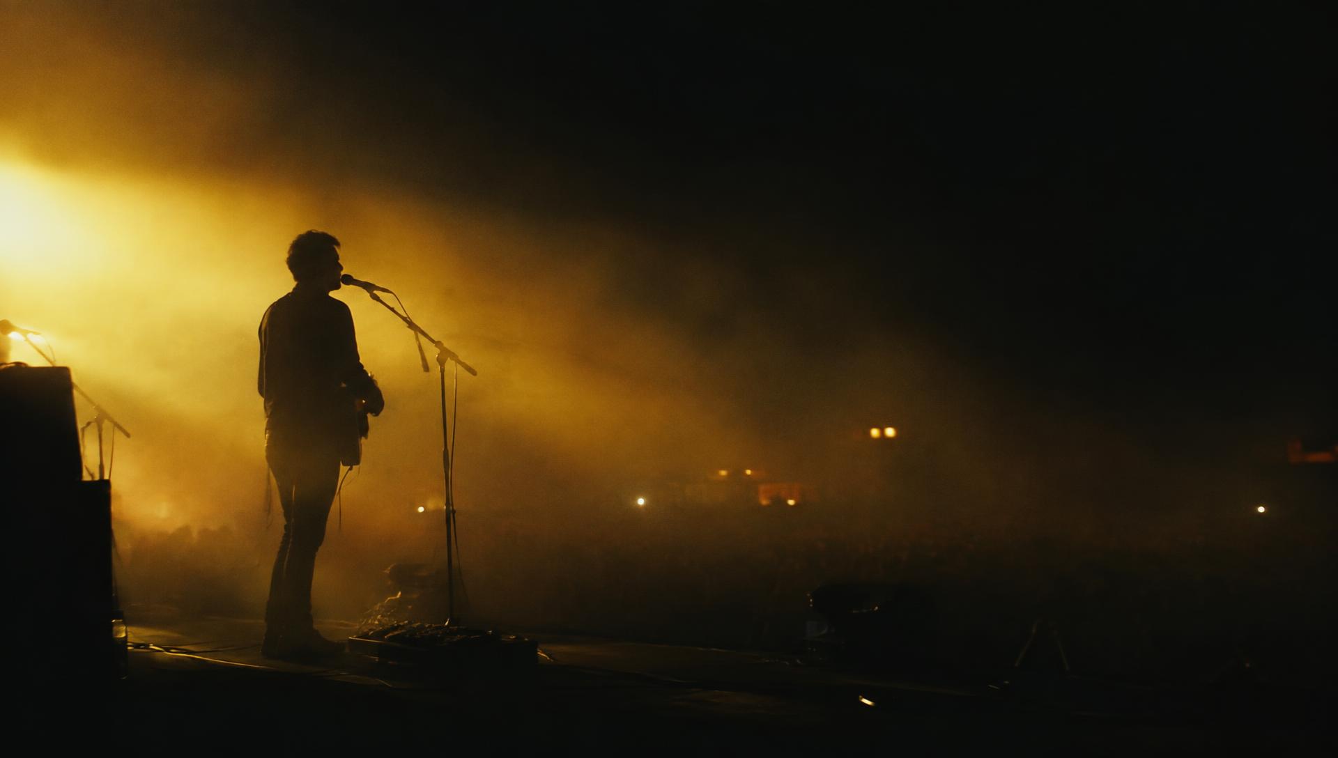 A lone performer silhouetted on a hazy stage under warm light